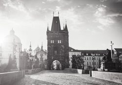 Vintage retro hipster style travel image of Charles bridge old town tower in Prague on sunrise, Czech Republic. With lens flare and light leak